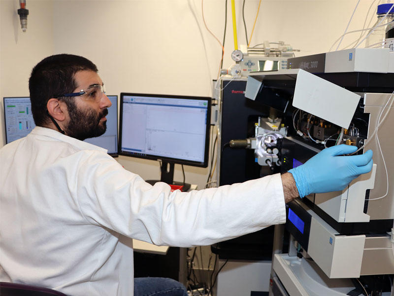 A photograph of a male scientist using the mass spectrometer.