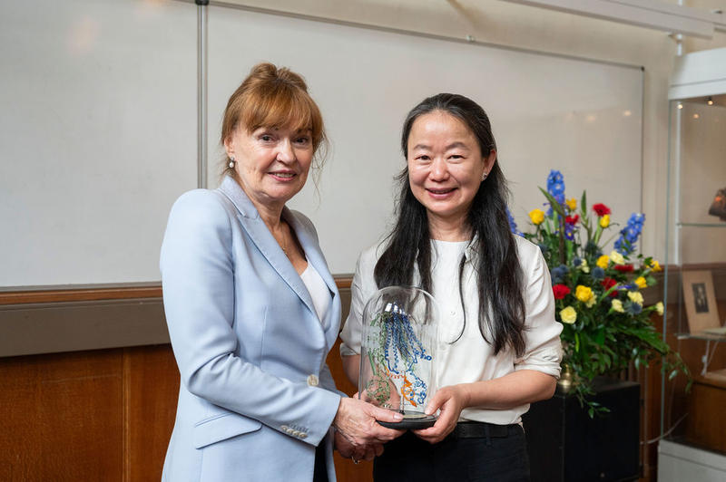 Professor Dame Carol Robinson and Professor Jue Chen, between them holding a glass-blown sculpture created by Terri Adams (Department of Chemistry), depicting an ABC transporter and interacting peptide