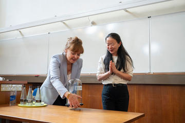 Professor Dame Carol Robinson turning a glass-blown sculpture created by Terri Adams (Department of Chemistry), depicting an ABC transporter and interacting peptide, Professor Jen Chue looking on appreciatively with hands clasped.