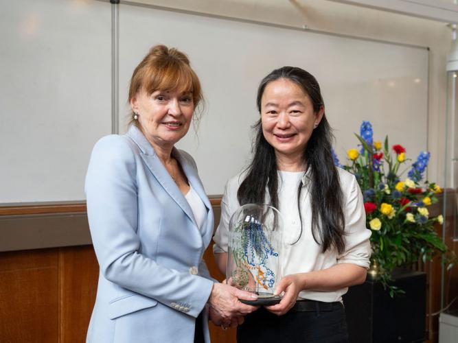 Professor Dame Carol Robinson and Professor Jue Chen, between them holding a glass-blown sculpture created by Terri Adams (Department of Chemistry), depicting an ABC transporter and interacting peptide