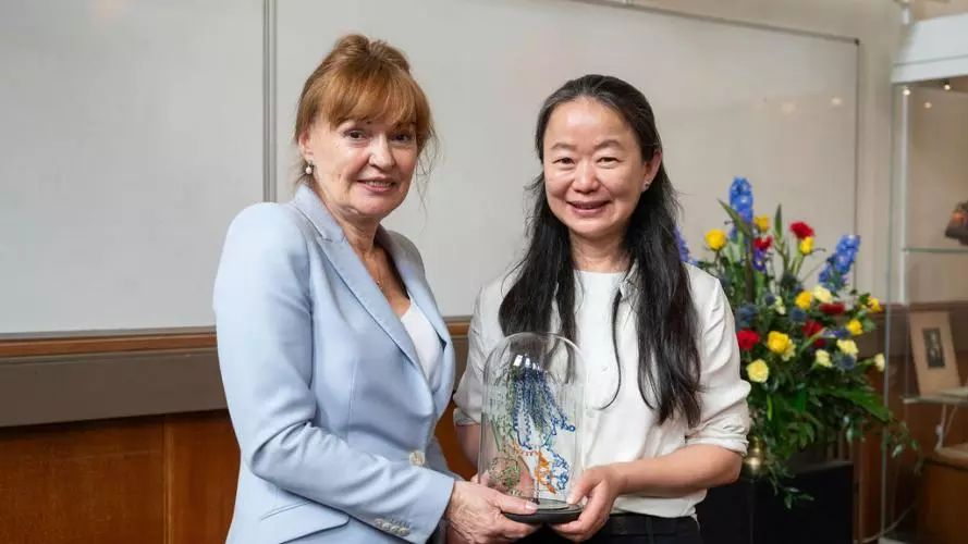 Professor Dame Carol Robinson and Professor Jue Chen, between them holding a glass-blown sculpture created by Terri Adams (Department of Chemistry), depicting an ABC transporter and interacting peptide