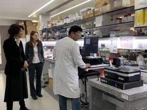 Photo of Dr Manish Kushwash explaining the mass photometry device to Chi Onwurah.