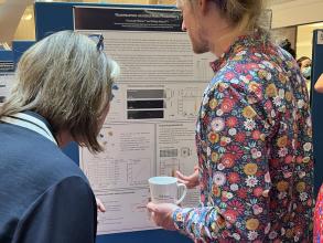 A photograph of Emanuel Pfitzner presenting his poster to a colleague.