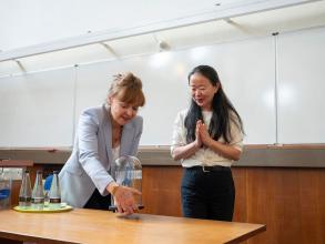 Professor Dame Carol Robinson turning a glass-blown sculpture created by Terri Adams (Department of Chemistry), depicting an ABC transporter and interacting peptide, Professor Jen Chue looking on appreciatively with hands clasped.