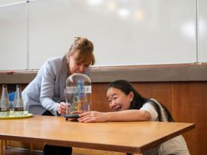 Professor Jue Chen and Professor Carol Robinson both smiling, looking at the glass-blown sculpture commemorating the Oxford Lecture Award 2026