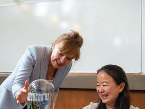 Professor Dame Carol Robinson and Professor Chue smiling while examining a glass-blown sculpture, created by Terri Adams, depicting an ABC transporter and interacting peptide.