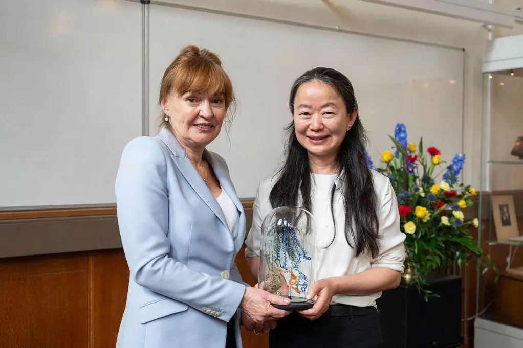 Professor Dame Carol Robinson and Professor Jue Chen, between them holding a glass-blown sculpture created by Terri Adams (Department of Chemistry), depicting an ABC transporter and interacting peptide